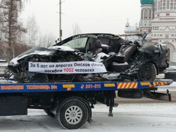 По улицам Омска эвакуаторы провезли разбитые машины с пугающим текстом на плакатах